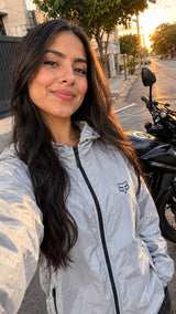 Selfie de motociclista con chaqueta cortavientos gris junto a su moto