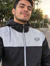 Hombre con chaqueta cortavientos negra con panel gris y capucha