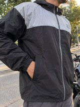 Detalle de chaqueta cortavientos negra: bolsillo lateral y puño elástico